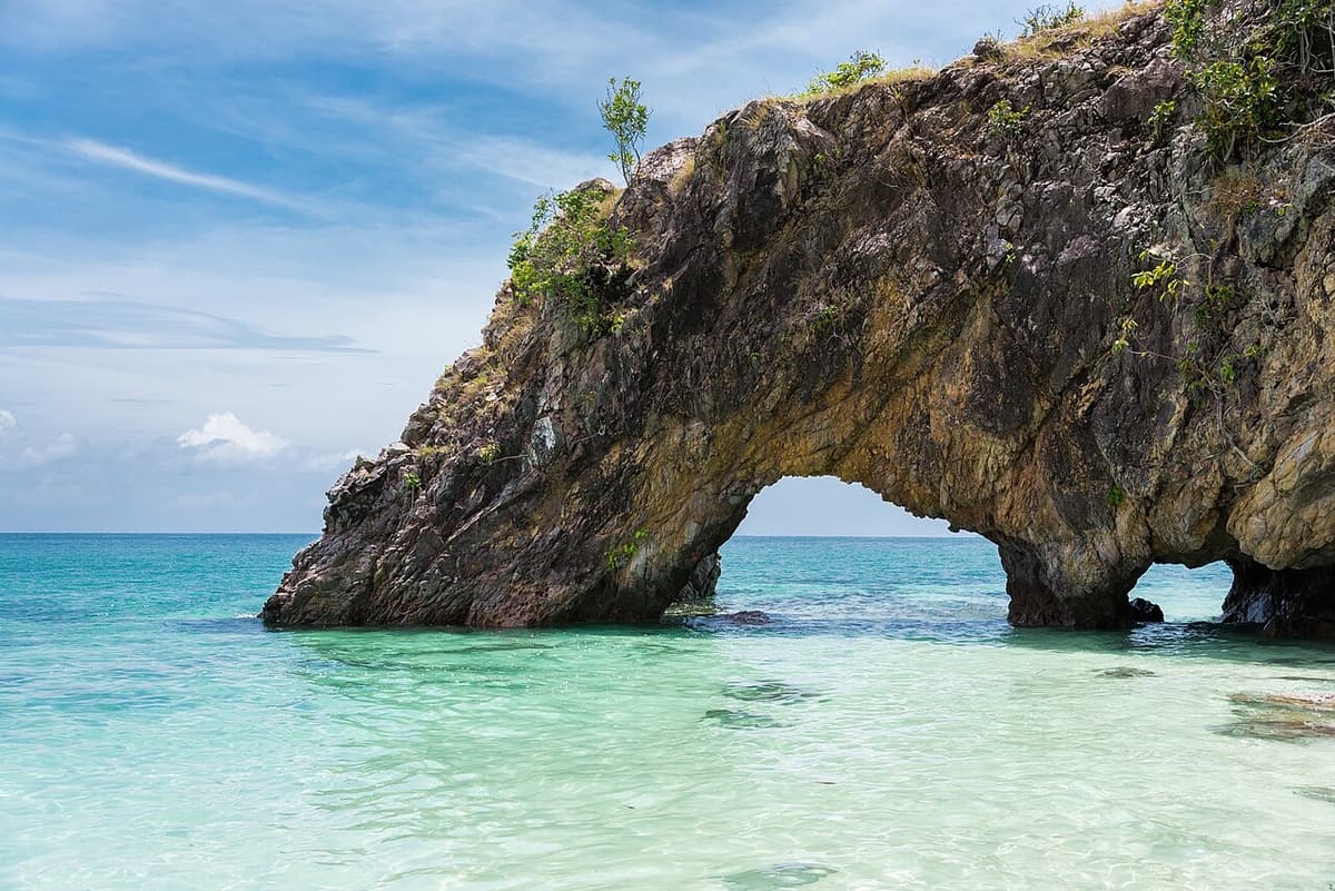 The natural stone arch of Koh Khai standing in clear turquoise water