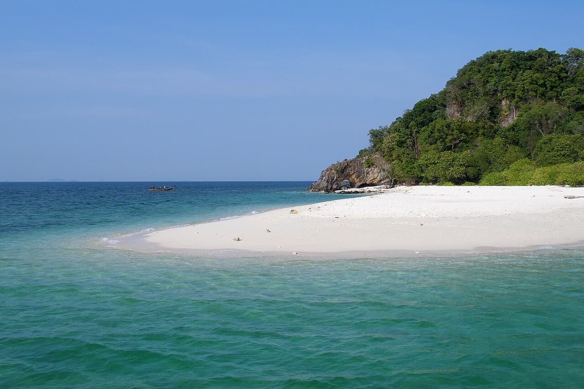 A white sandbar and green hills on Koh Rawi