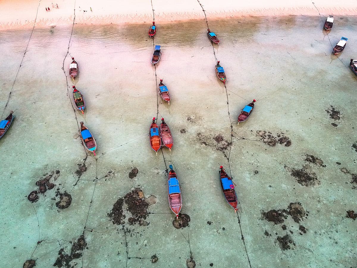 Longtail boats seen from above in the turquoise shallows off Koh Lipe