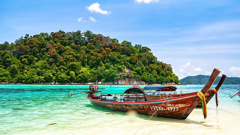 Longtail boats pulled up on a white beach in Tarutao National Marine Park